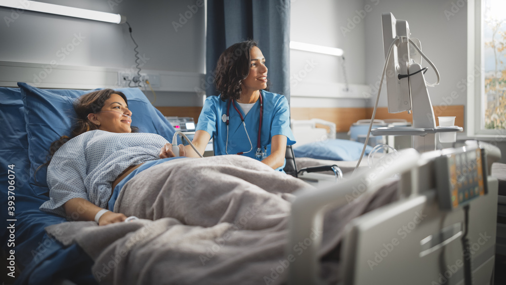 Hospital Ward: Beautiful Pregnant Hispanic Woman Getting Sonogram / Ultrasound Screening / Scan, Female Latin Obstetrician Wearing Face Mask Checks Picture of the Healthy Baby on the Computer Screen Hospital Ward: Beautiful Pregnant Hispanic Woman Getting Sonogram / Ultrasound Screening / Scan, Female Latin Obstetrician Wearing Face Mask Checks Picture of the Healthy Baby on the Computer Screen