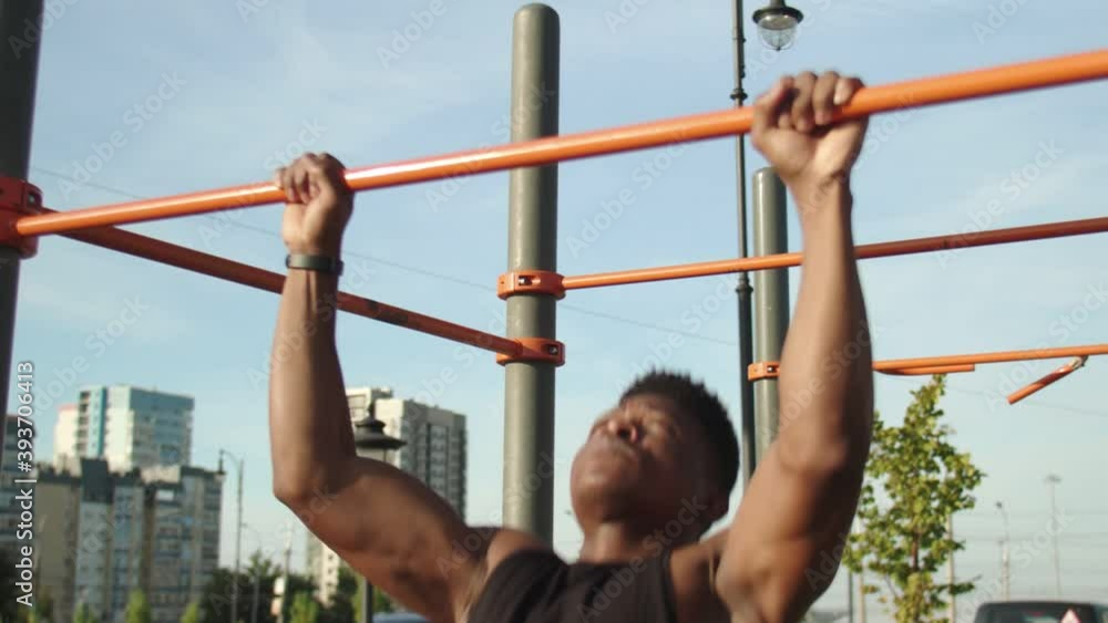 Youmg african man doing pull ups on horizontal workout outdoors Youmg african man doing pull ups on horizontal workout outdoors