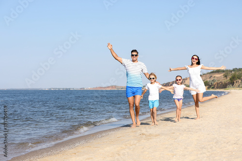 Happy family walking on sandy beach near sea. Summer holidays