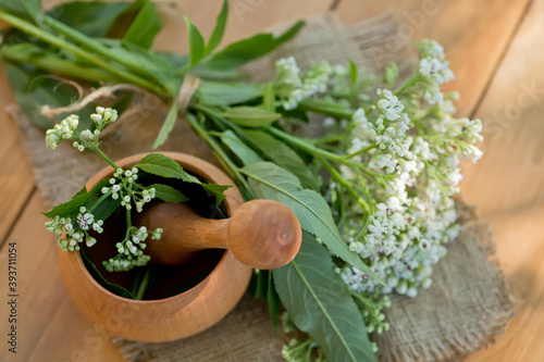 Fresh Valeriana officinalis flowers in wooden mortar. Valerian tablets among white flowers are on table. Used as an alternative to valium in natural medicine