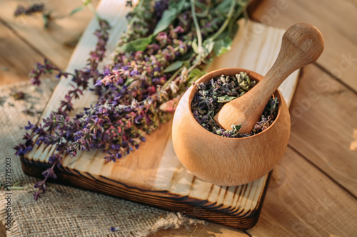 Salvia pratensis , meadow clary or meadow sage purple fresh flowers near mortar with cooked dried herb. Medicinal herbs. self-medication. photo