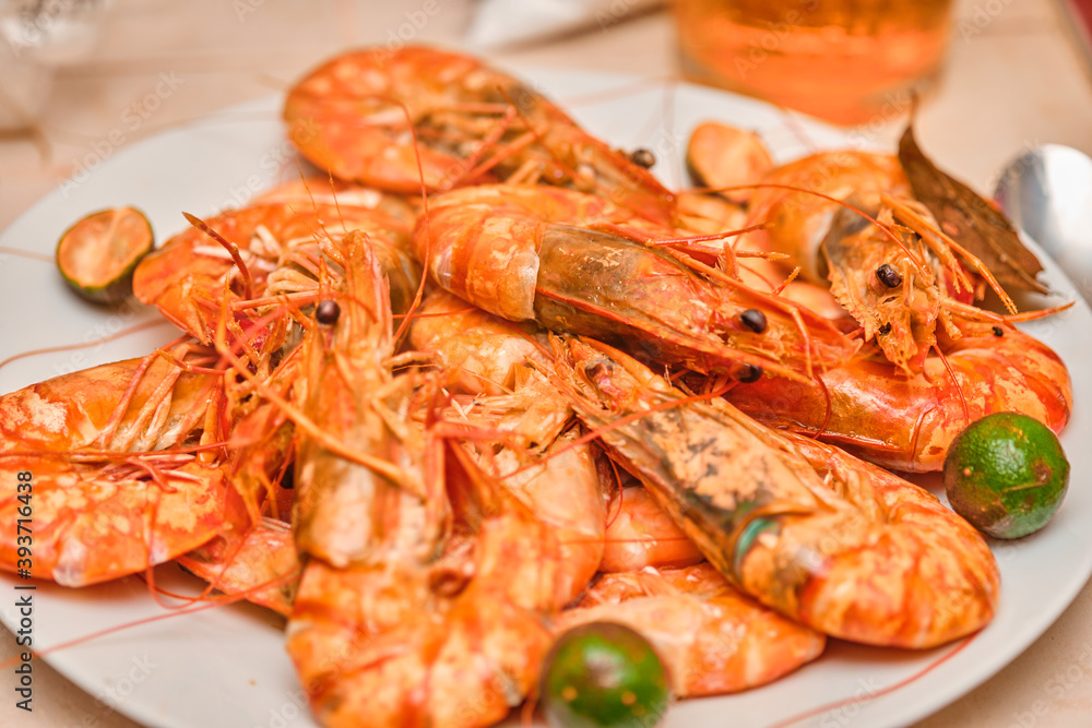 Red cooked prawns on a white plate with vegetables.