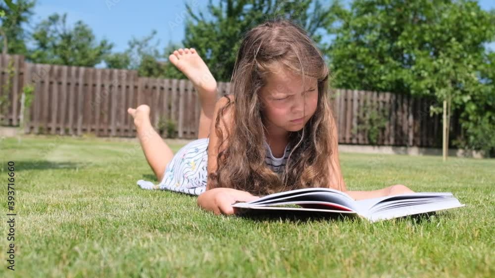A girl reads a book in the garden on the grass. A girl reads a book in the garden on the grass.