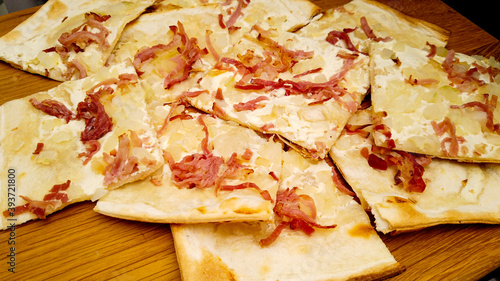 Tarte Flambee is a kind of French pizza from Alsace made from a very thin layer of pastry topped with sour cream, chopped onions and bacon photo