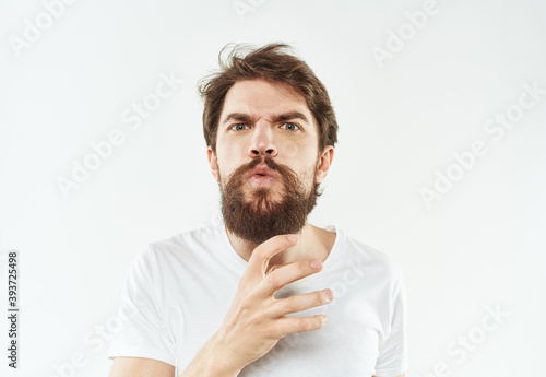 A young man in a white T-shirt gestures with his hands emotions irritability stress