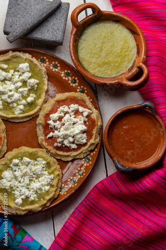 Mexican picaditas with sauce and fresh cheese on white background