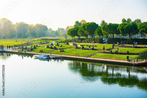 crowd of multiethnical people chilling and relaxing in a outdoor public park wearing warm winter clothes.nature landscapes with green trees and grass. concept about movement of the persons and leisure