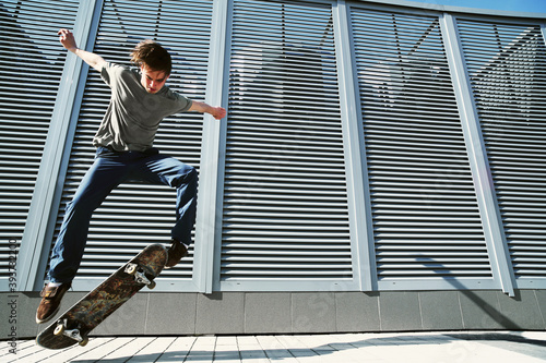 Φωτογραφία Young Caucasian man jumping on a skateboard on the street.