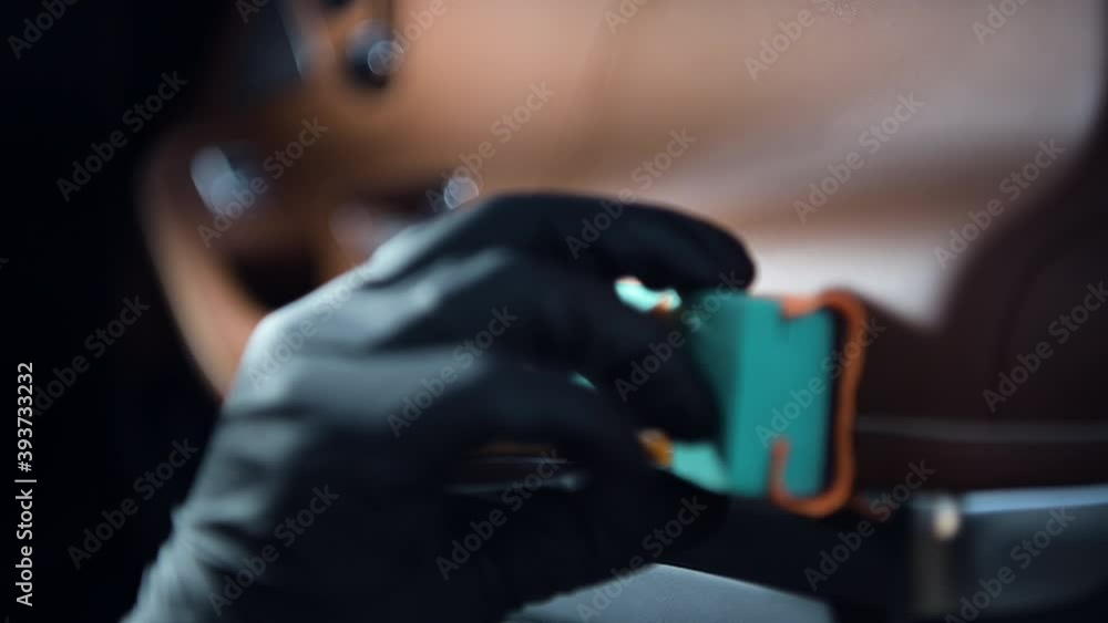 Closeup of car detailing process. Man hand apply nano protective coating on a luxury car door covered with a leather. Closeup of car detailing process. Man hand apply nano protective coating on a luxury car door covered with a leather.