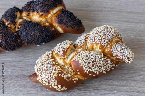 2 braided long lye bread rolls with sesame and poppy seeds