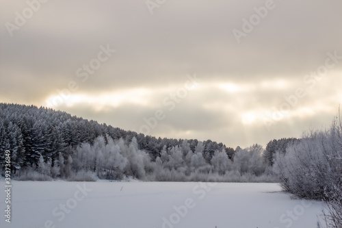 Dramatic sky with clouds over the winter forest and lake. © Анатолий Савицкий