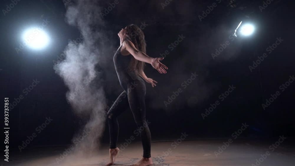 woman dancer is making clouds of dust or powder by movement of hair, silhouette in darkness woman dancer is making clouds of dust or powder by movement of hair, silhouette in darkness