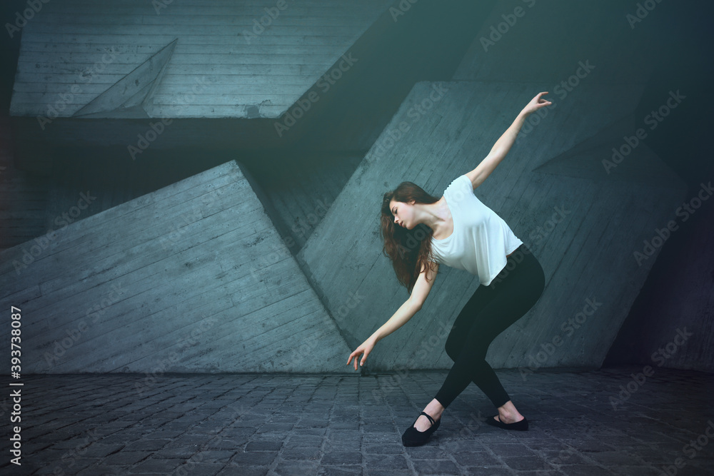 Young caucasian ballerina dancing ballet on the street in summer.