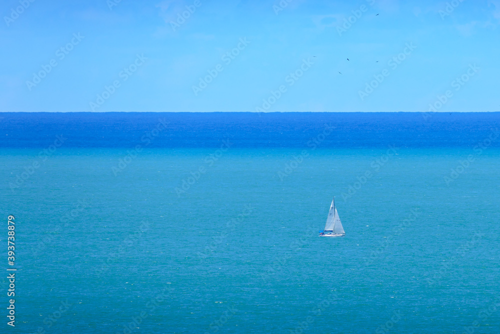 Minimalist: white sailboat in turquoise and blue seas