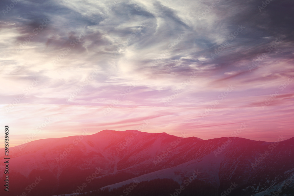 Obraz premium Panoramic view of snowy mountain peaks in winter at sunset.