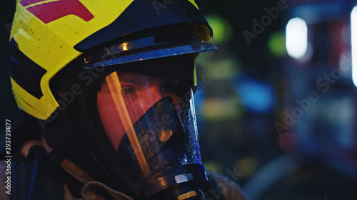 Close up, portrait of firefighter wearing gas mask in front of the burning house. High quality photo © CameraCraft