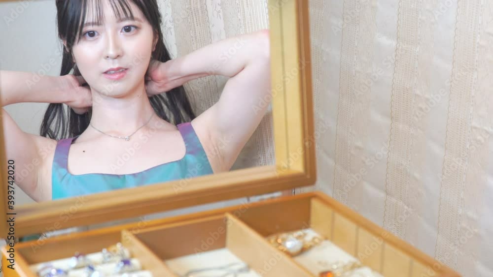 ネックレスを外して仕舞う若い日本人の女性 ネックレスを外して仕舞う若い日本人の女性