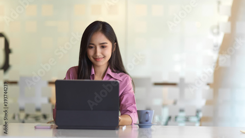 Female office worker working with tablet in glass partition office room