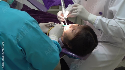 asian dentist doing fluoride treatment to young girl in dental clinic