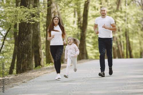 Family in a summer forest. Woman and man in a white t-shirts. Daughter with parents.