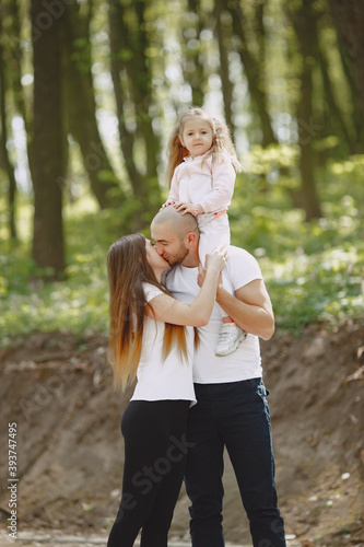 Family in a summer forest. Woman and man in a white t-shirts. Daughter with parents. © hetmanstock2
