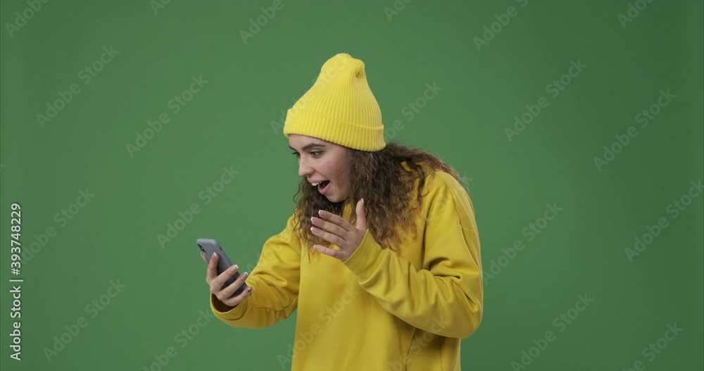 Woman astonished on receiving good news using mobile phone over green screen Woman astonished on receiving good news using mobile phone over green screen