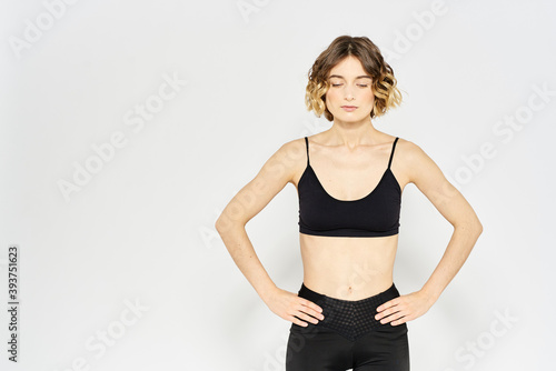 Slender girl in sportswear on a light background leggings hairstyle cropped view