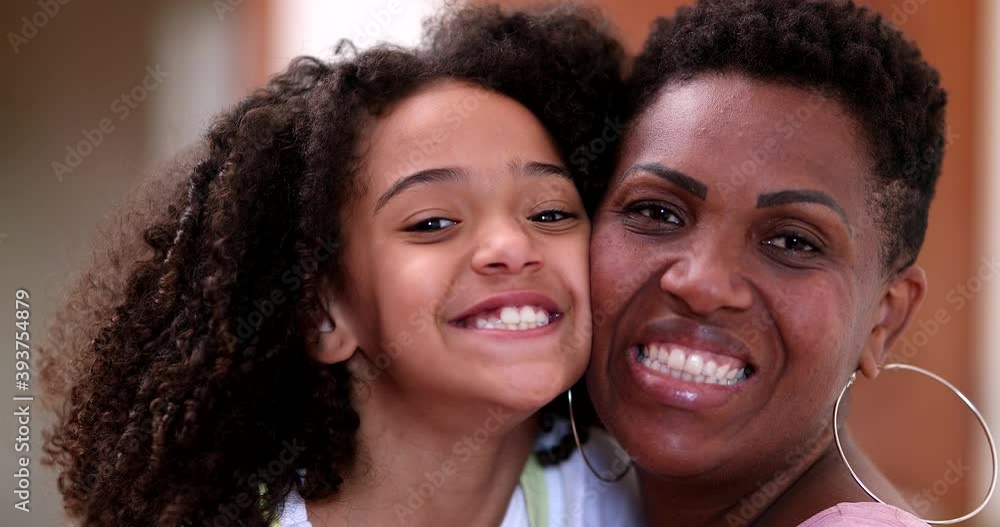 Happy African mother and daughter posing to camera smiling, cheek to cheek Happy African mother and daughter posing to camera smiling, cheek to cheek
