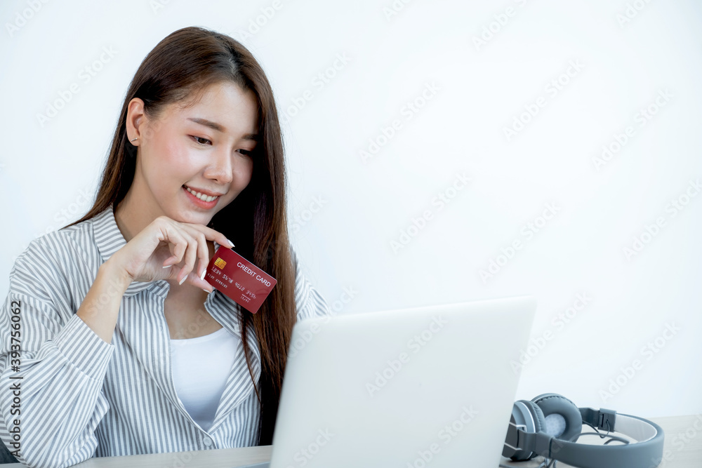 Portrait of a lovely young Asian beautiful woman with long hair holding a red credit card, her eyes sparklingly at the camera. Ready to pay shopping according to discounted products Portrait of a lovely young Asian beautiful woman with long hair holding a red credit card, her eyes sparklingly at the camera. Ready to pay shopping according to discounted products