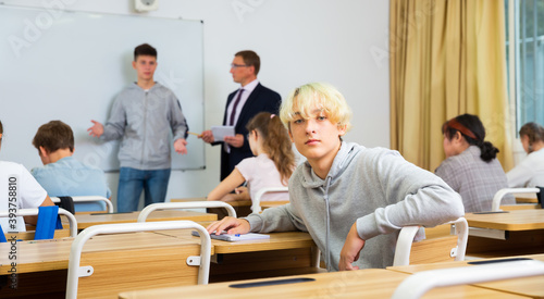 Young teenager is sitting at the desk in the classroom