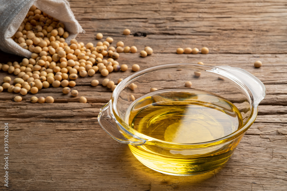 Soybean oil in glass bowl with Soybean on wooden table Soybean oil in glass bowl with Soybean on wooden table