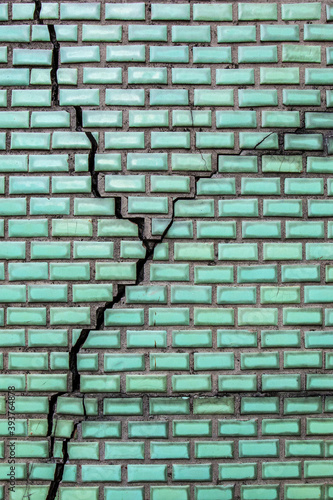 Cracks on green brick wall.