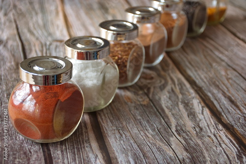 Various colorful herbs and spices in glass container on wooden background