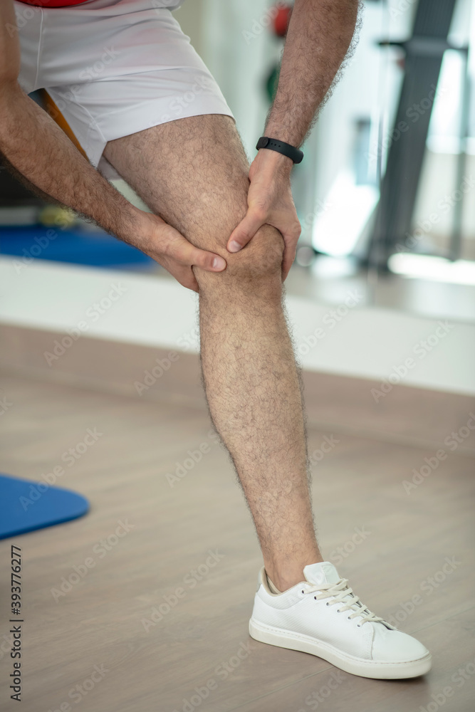Naklejka premium Close-up of male hands massaging painful knee