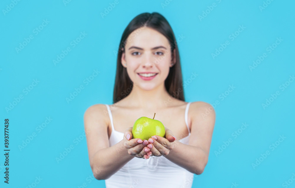 Woman eat green apple. Portrait of young beautiful happy smiling woman with green apples. Healthy diet food. Woman with perfect smile holding apple, blue background Woman eat green apple. Portrait of young beautiful happy smiling woman with green apples. Healthy diet food. Woman with perfect smile holding apple, blue background