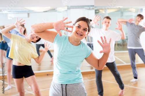 Portrait of emotional teenager girl doing dance workout during group class in studio