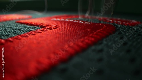 Machine embroiders red number on green hockey club uniform photo