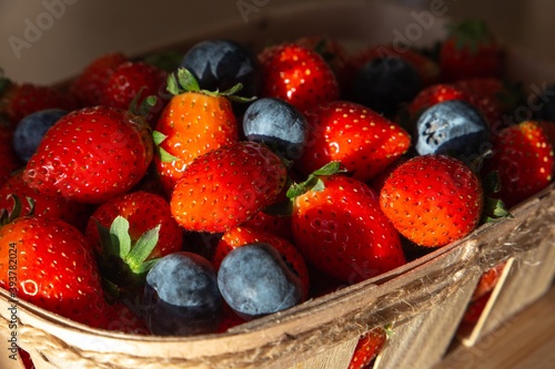  Strawberries blueberries and raspberries on a wooden tray and light background