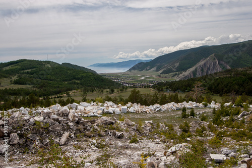 View from the old marble quarry to the village of Buguldeyka near Lake Baikal. A small village between the hills. A ridge of white marble in the foreground. Cloudy Horizontal. photo