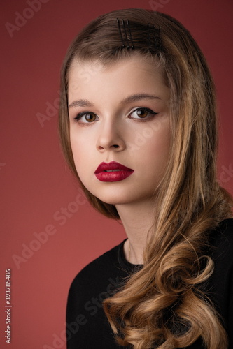 close-up portrait of a beautiful teen girl with bright red lipstick on a red background