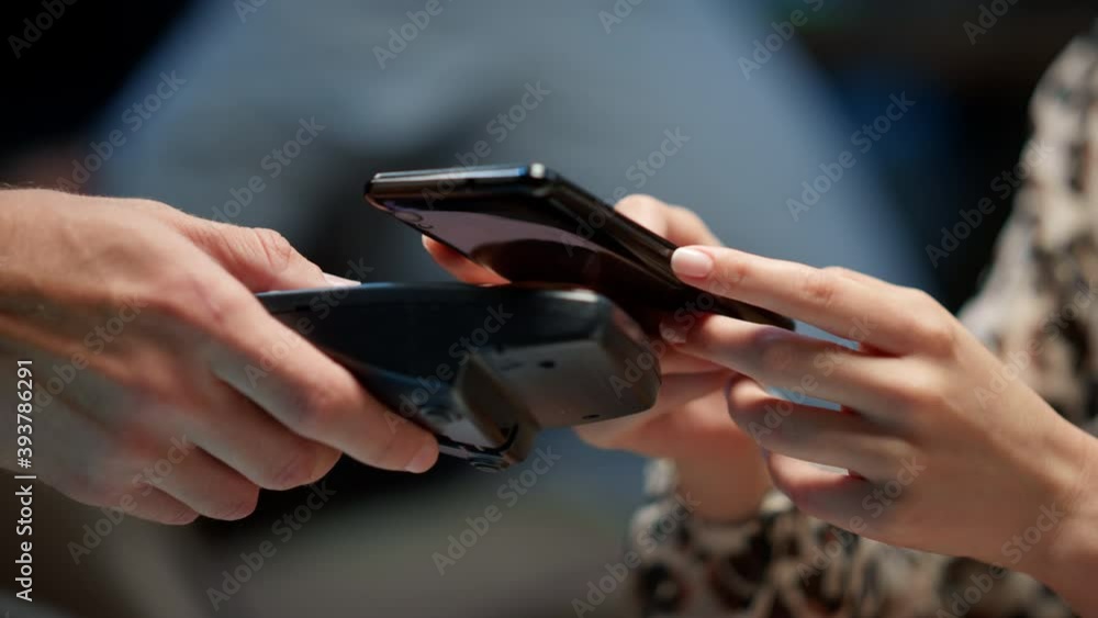 Closeup businesswoman hands paying with mobile phone over pos terminal Closeup businesswoman hands paying with mobile phone over pos terminal