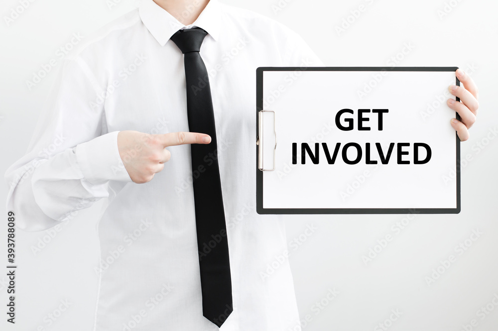 A businessman holds a folder with documents, the text on the folder is - GET INVOLVED. Business concept. A businessman holds a folder with documents, the text on the folder is - GET INVOLVED. Business concept.