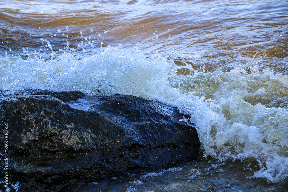 waves run onto the shore and crash against the rocks, creating many splashes and splashes near the shore. river surf in stormy weather near a stone pebble coast with foamy splashing waves. waves run onto the shore and crash against the rocks, creating many splashes and splashes near the shore. river surf in stormy weather near a stone pebble coast with foamy splashing waves.