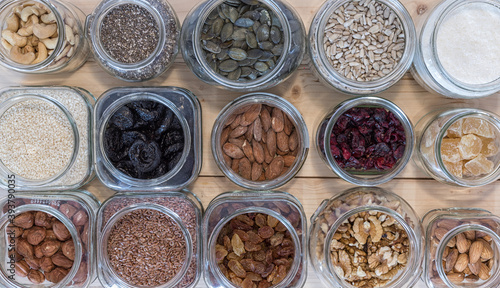 Seed,nut and dried fruits in various jars over wood background.
