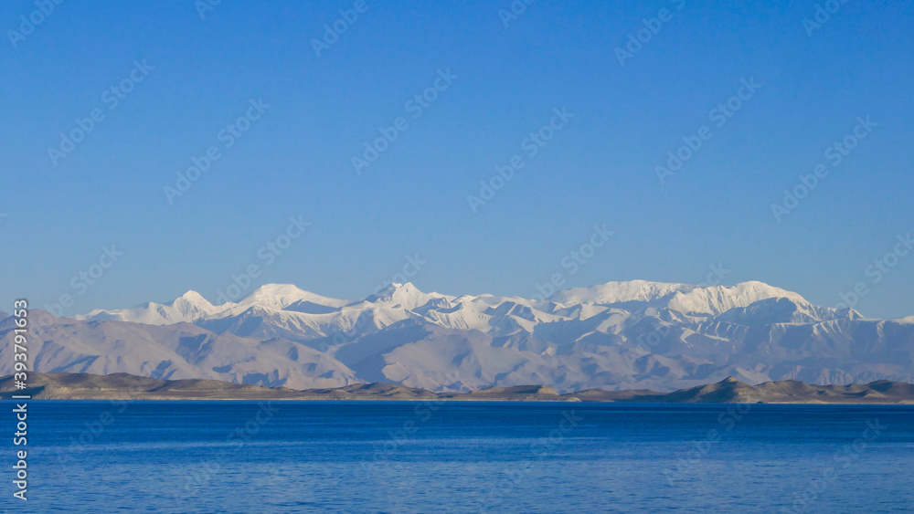 View from the shores of Karakul lake after sunrise, with Zulumart snow-capped mountain range in the background, Murghab district, Gorno-Badakshan, in the Pamir region of Tajikistan
