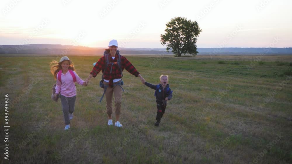 Mother and two children walking in the meadow at the sunset time. Silhouette happy beautiful family during the travelling. Concept of friendly family and travel. Mother and two children walking in the meadow at the sunset time. Silhouette happy beautiful family during the travelling. Concept of friendly family and travel.