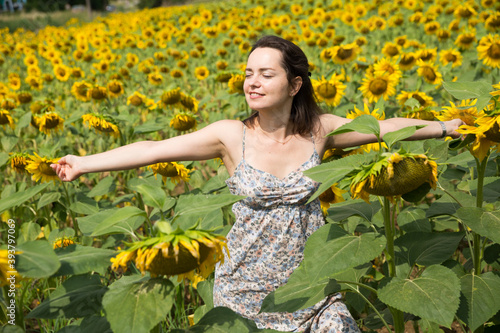 Young positive girl posing in sunflowers field and having fun