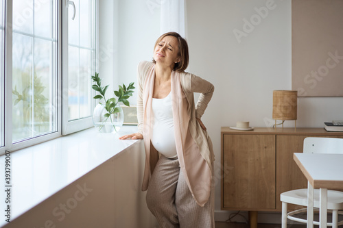 Healthcare, treatment. Young pregnant woman feeling sudden pain in her back. Future mom suffering from backpain. High quality photo