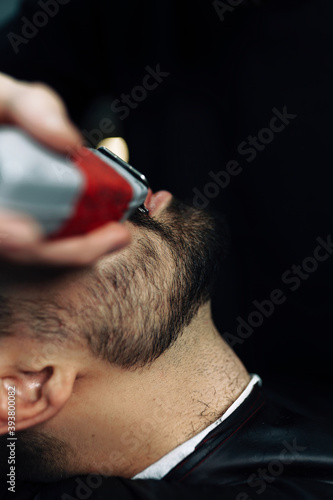 barber cuts his beard with a trimer close-up 