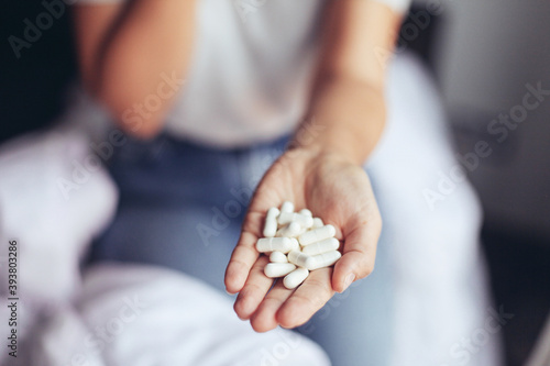 Close up picture of a woman's hand holding white pills